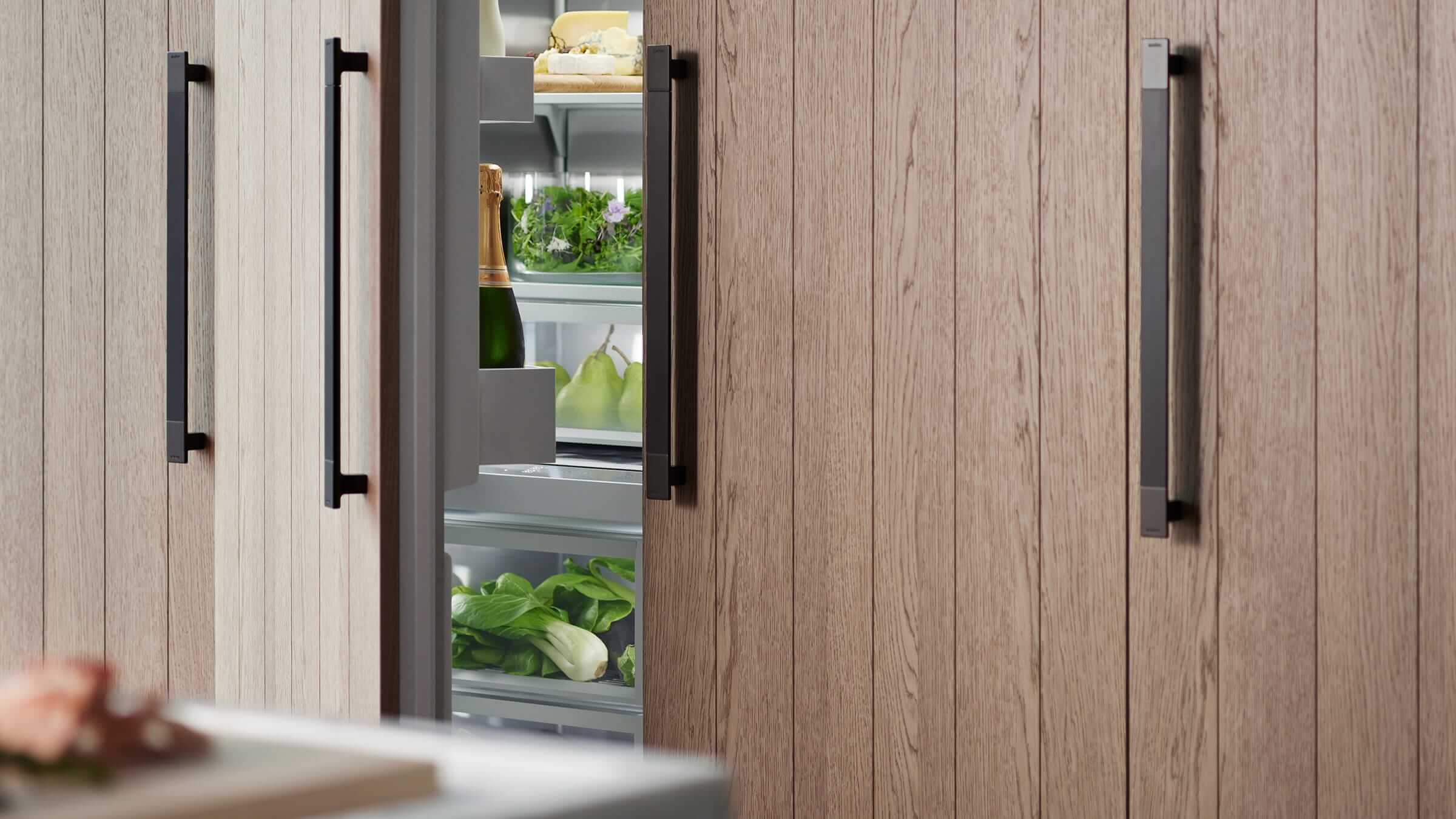 A modern kitchen setting with integrated column refrigeration under warm lighting