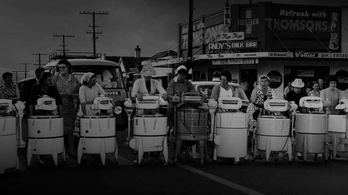 Women standing behind old washing machines